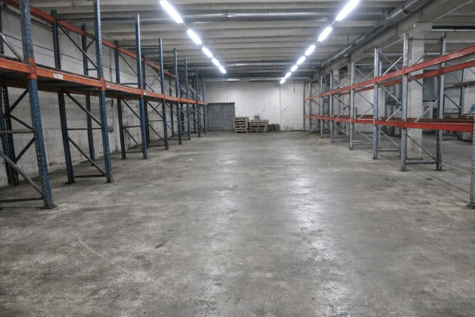 Leere Lagerhalle mit sauberem Betonboden und zusammengestellten Transportpaletten